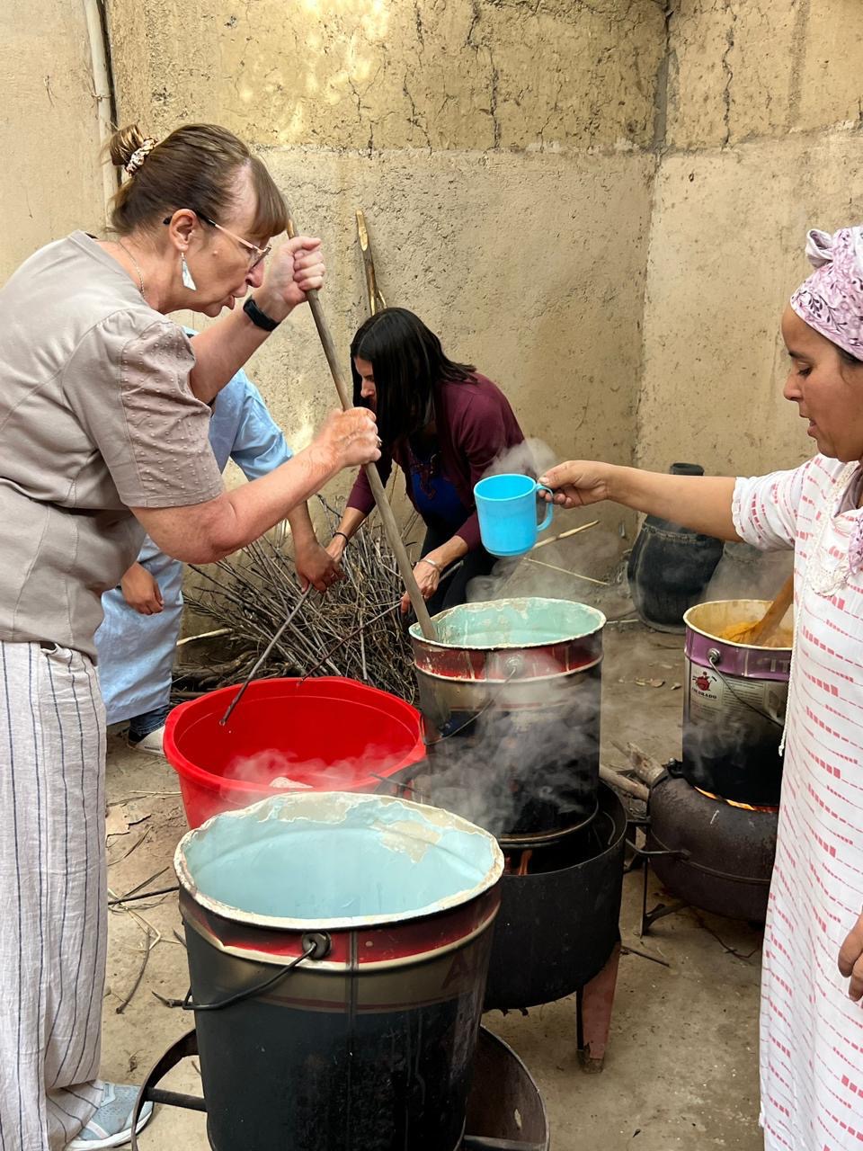 An artisan lifting freshly dyed orange wool from the pot