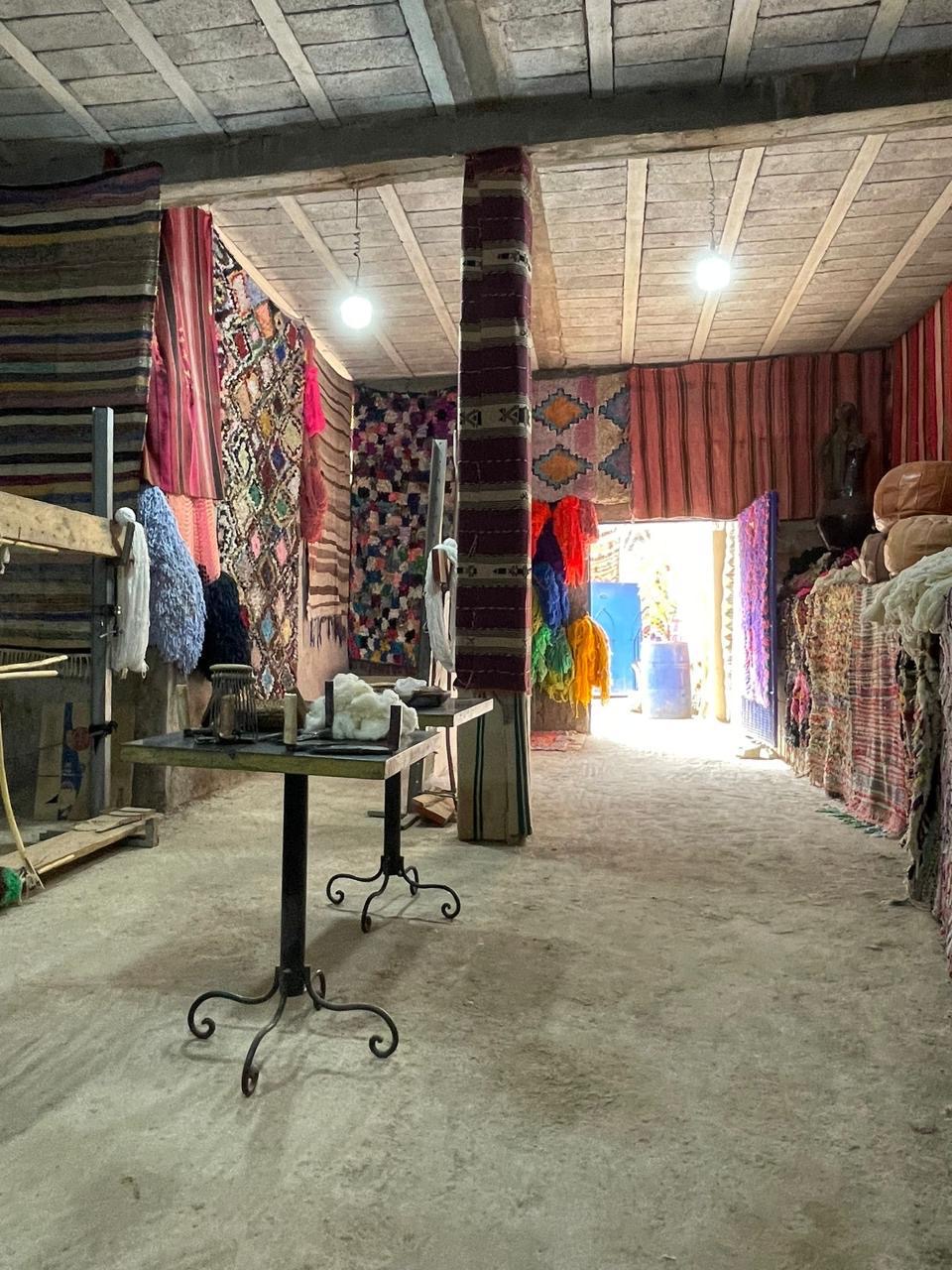 Inside the rug workshop, walls hung with finished pieces