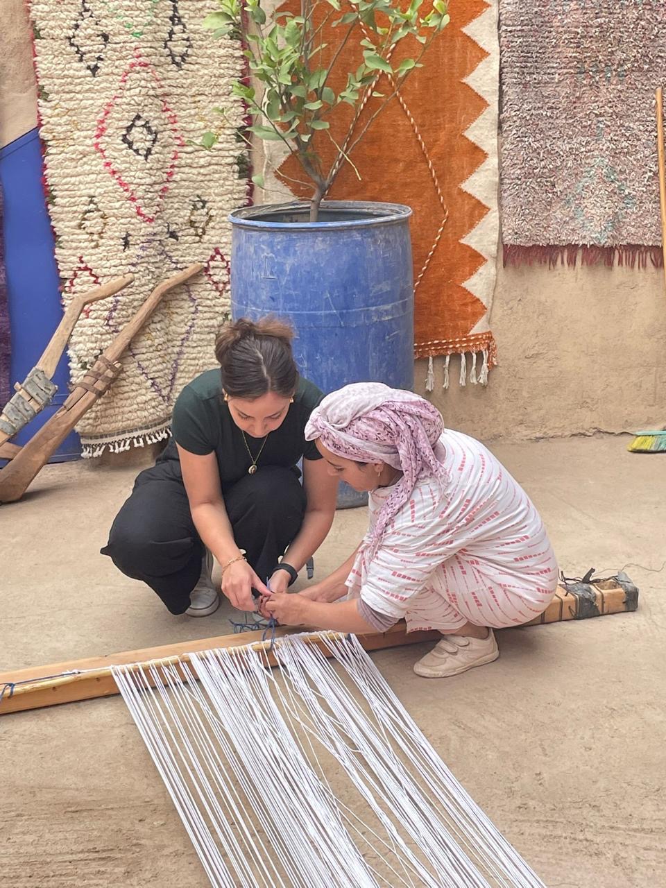 A guest helping an artisan tie the warp threads
