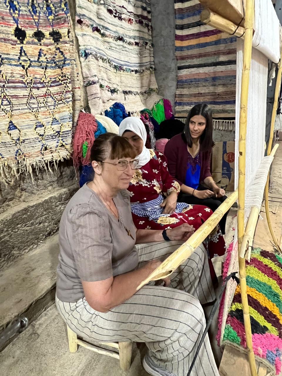Guests weaving at the loom beside the artisans